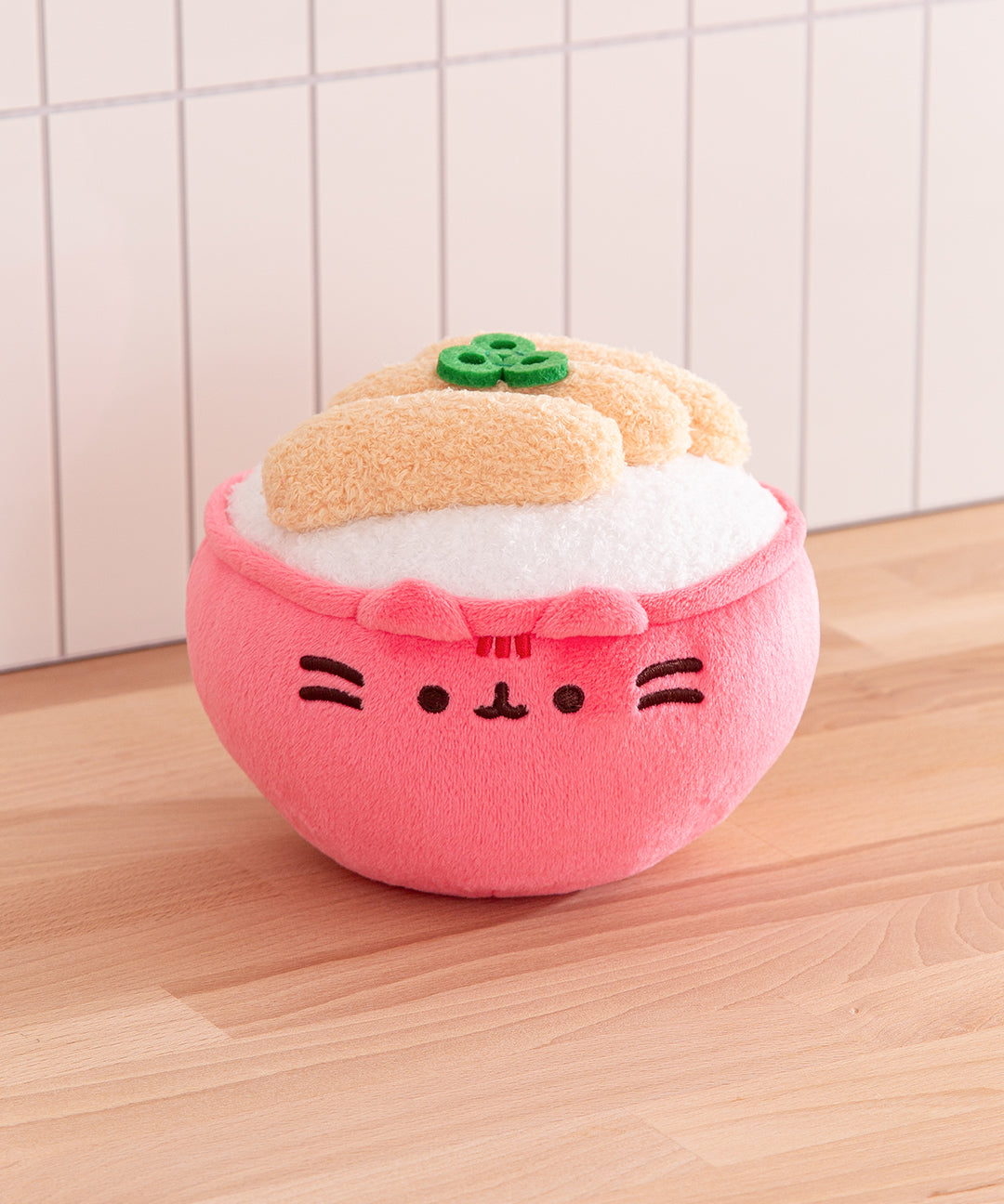 Plush toy shaped like a cartoon bun with a pink bun and white filling on a wooden surface.