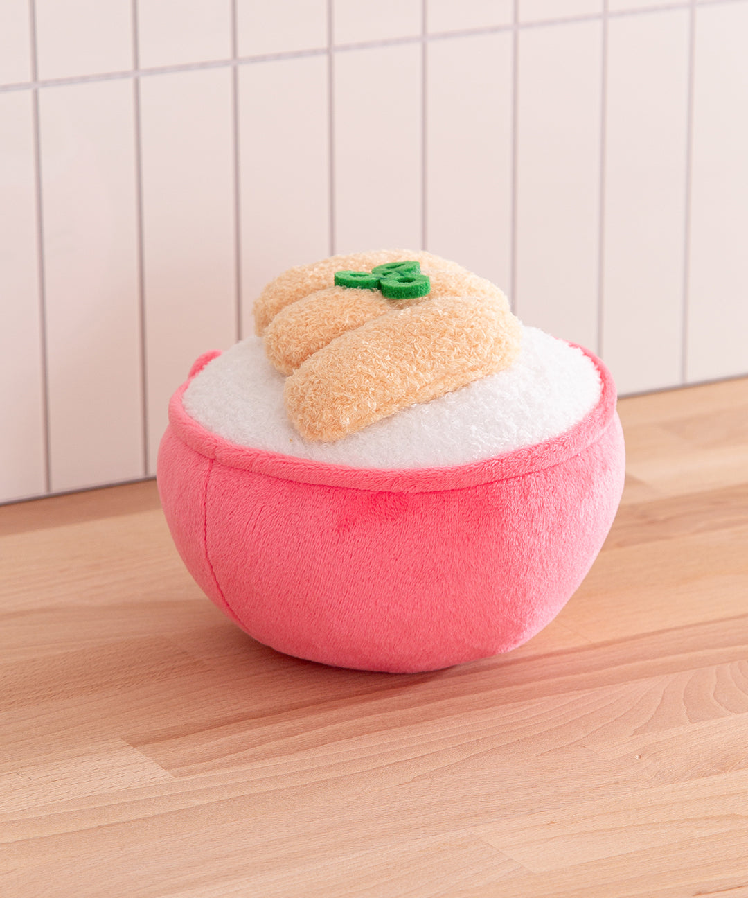Plush toy resembling a peach with a pink base on a wooden surface.