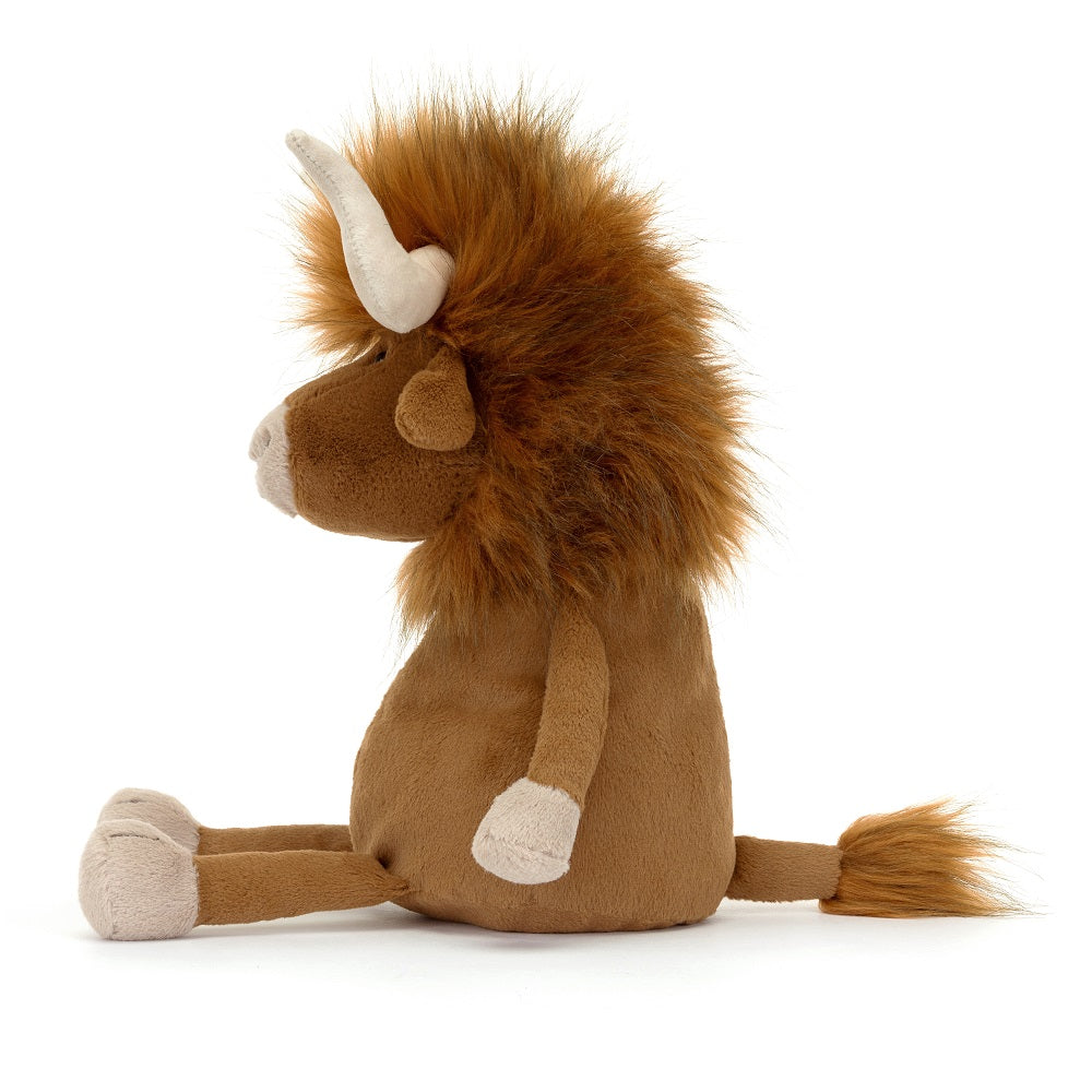 Profile view of a brown stuffed yak with fuzzy hair and ivory horns, seated.