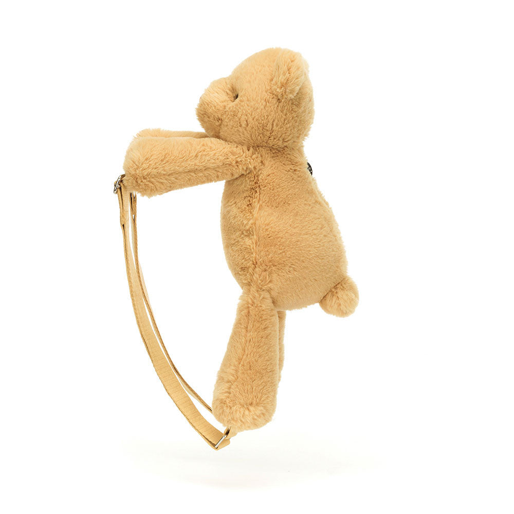 Tan stuffed bear with strap, side view.