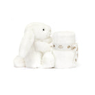 White plush bunny toy and rolled blanket with a branded ribbon.