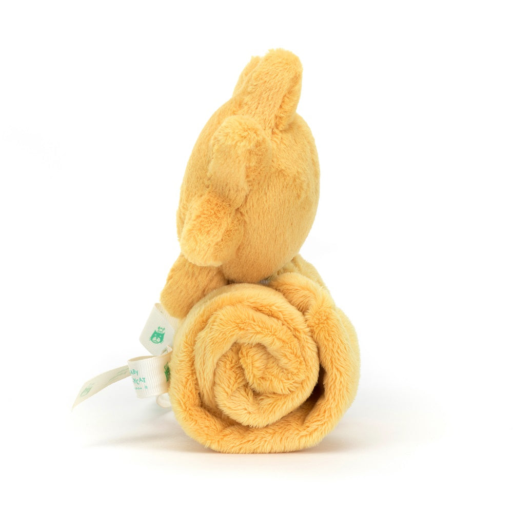 Back view of a rolled-up, golden-yellow plush bear toy with a white label.