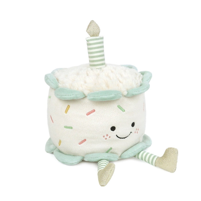 Plush birthday cake toy with a smiling face, sprinkles, and a striped candle.