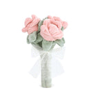 Stuffed pink rose bouquet with green leaves and a white bow.