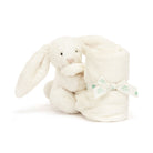 White plush bunny holding rolled white blanket with ribbon.