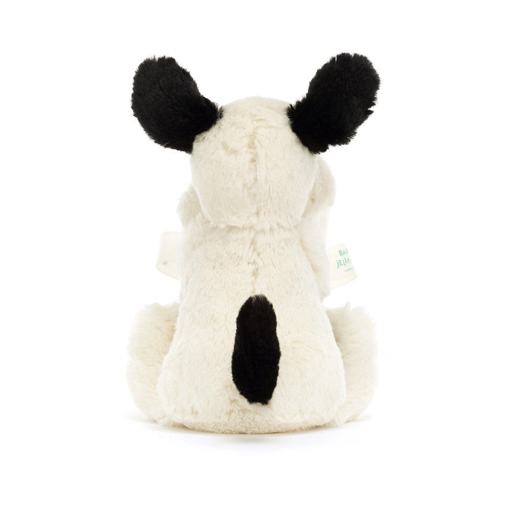 Rear view of a cream-colored stuffed dog with black ears and a black spot on its back.