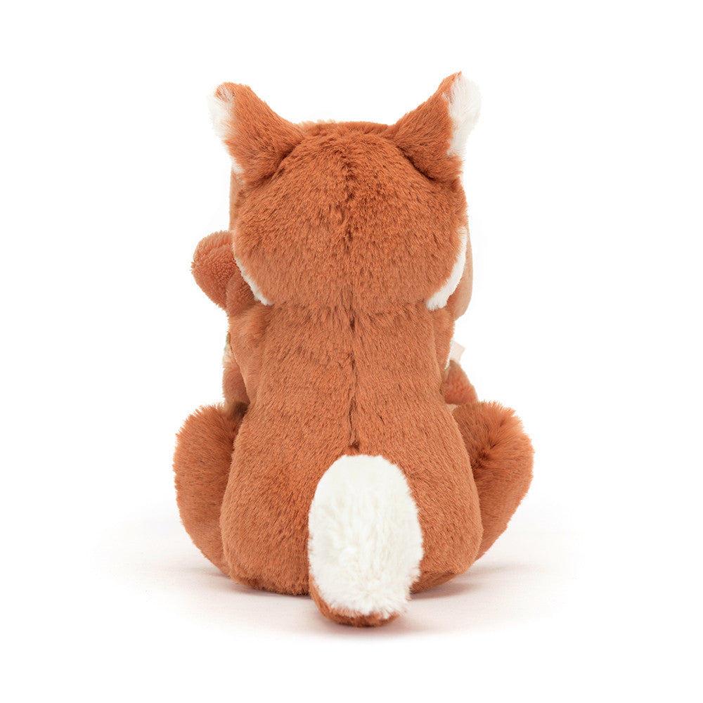 Rear view of a stuffed, light brown fox toy with white ear tips and tail.