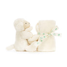 A white lamb stuffed animal next to a rolled blanket with a ribbon around it.