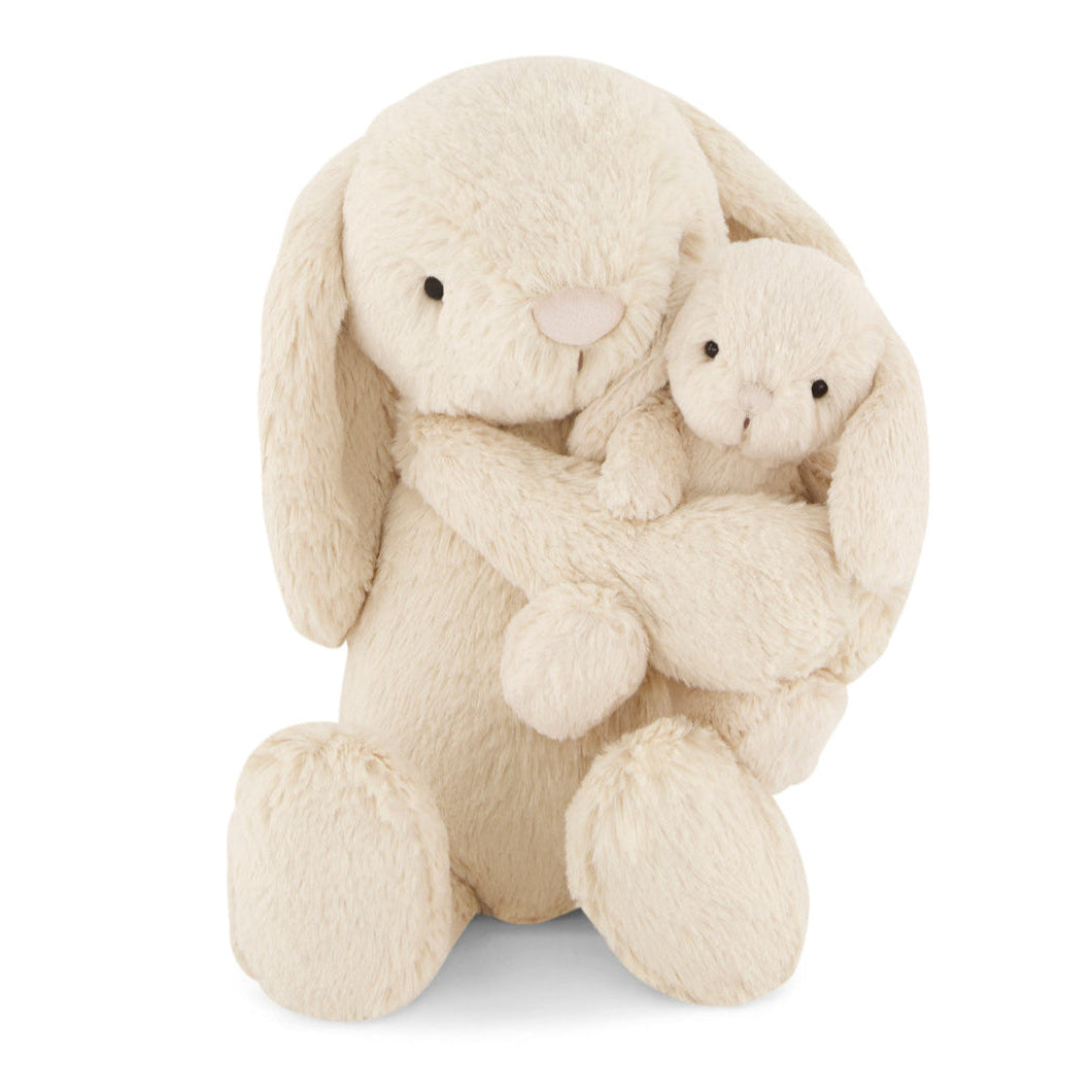 Cream-colored bunny plush toy holding a smaller cream-colored bear plush toy on a white background