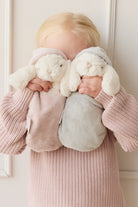 Child holding two stuffed bunny comfort toys. Child wears a pink knit sweater.