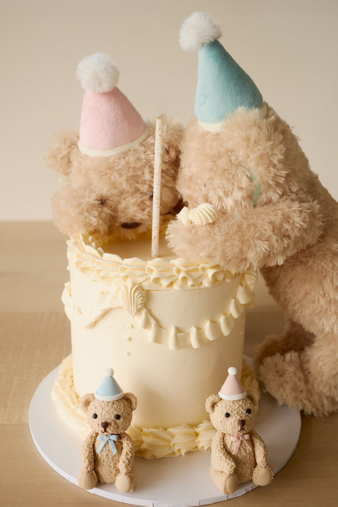 Teddy bears with party hats around a birthday cake.