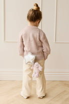 Back view of girl in pink sweater and tan pants, wearing a star purse with a bunny charm.
