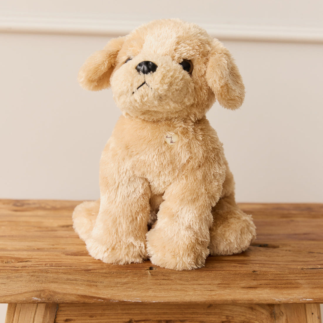 Stuffed golden retriever puppy sitting on a wooden surface.