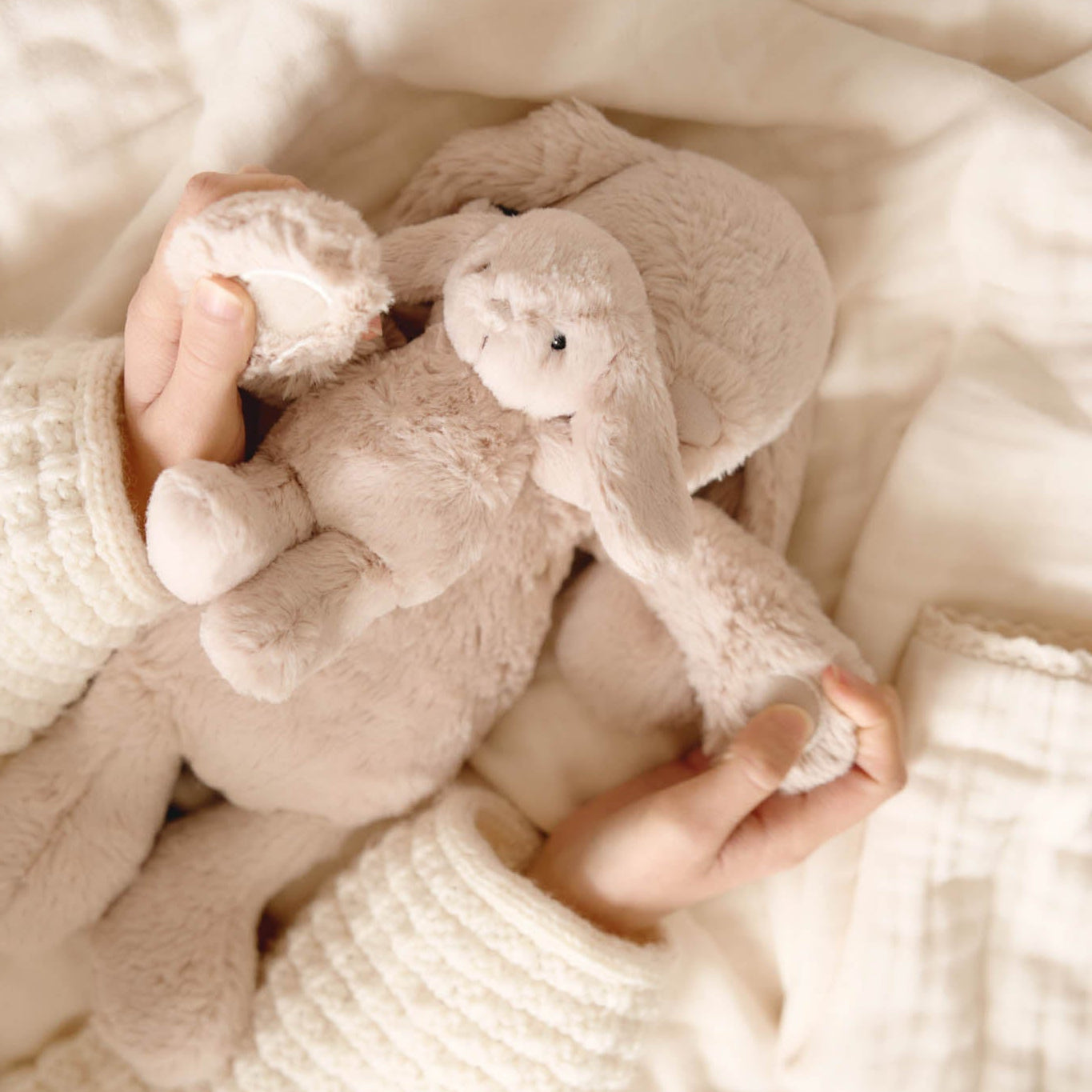 Person holding two plush toys wrapped in a soft blanket