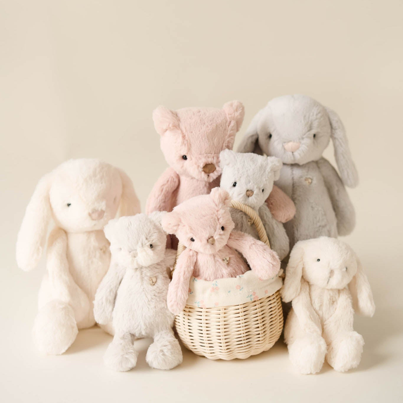Group of soft pastel-colored stuffed animals; rabbits and bears, one in a basket.