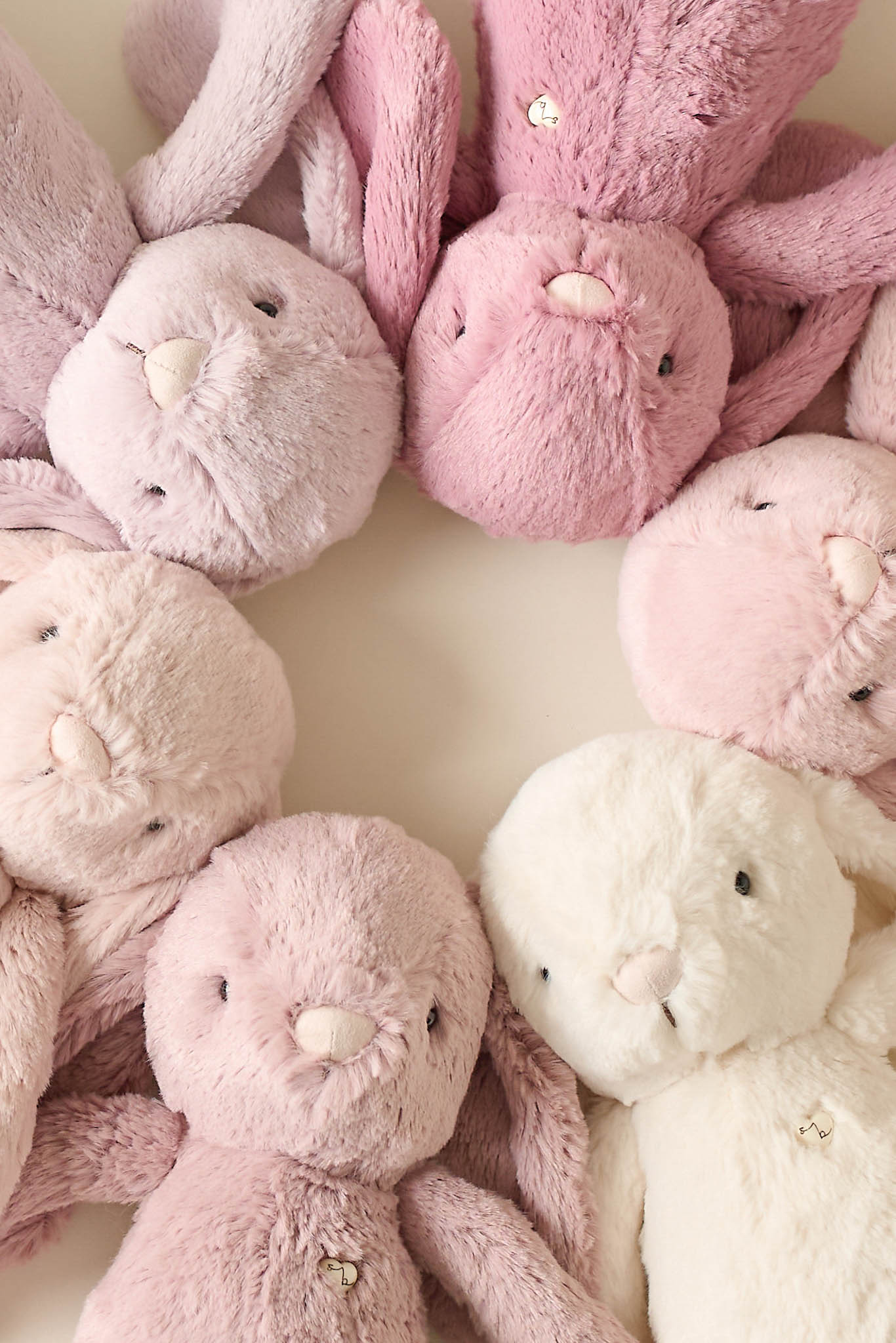 Circle of plush bunny toys in various shades of pink and white.