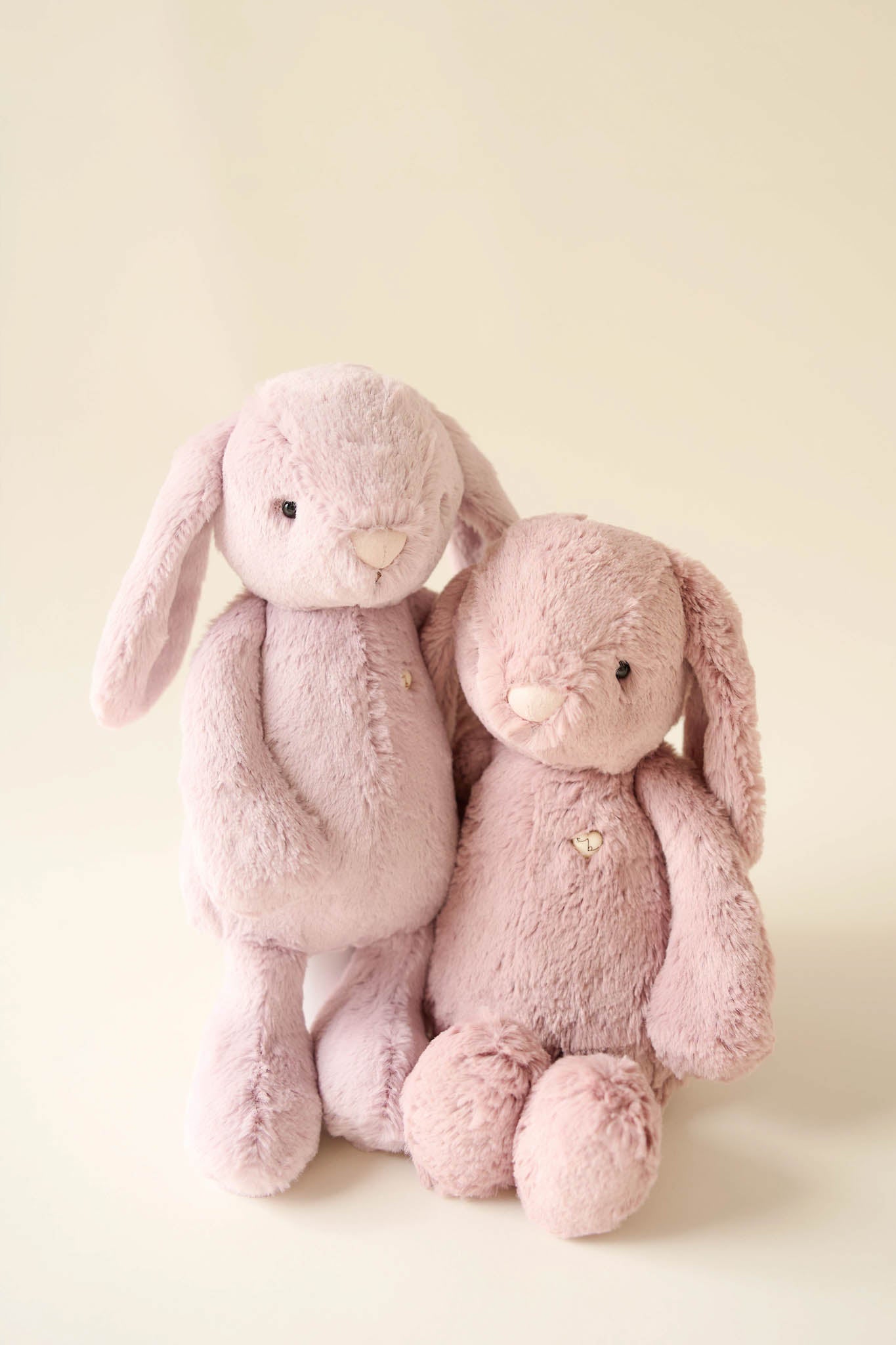 Two pink stuffed rabbits standing next to each other.