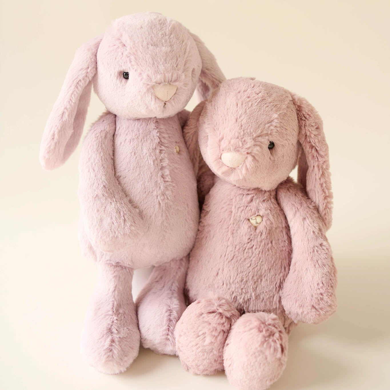 Two pink stuffed rabbits standing next to each other.