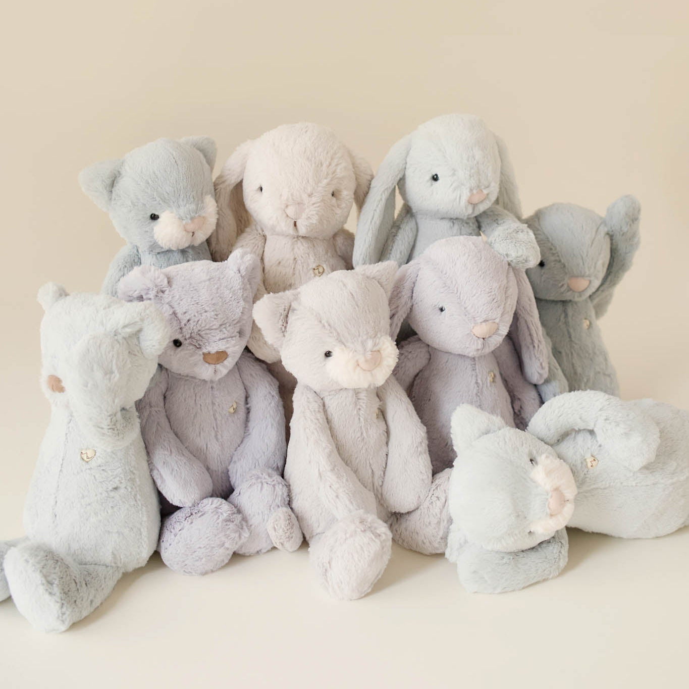 Group of plush teddy bears and bunnies in shades of grey and white.