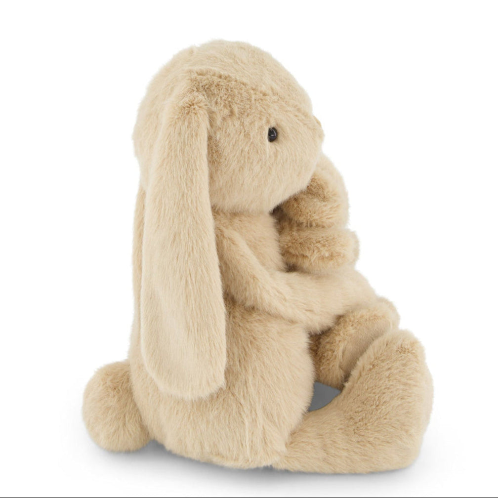Side view of a plush, tan bunny rabbit toy sitting.