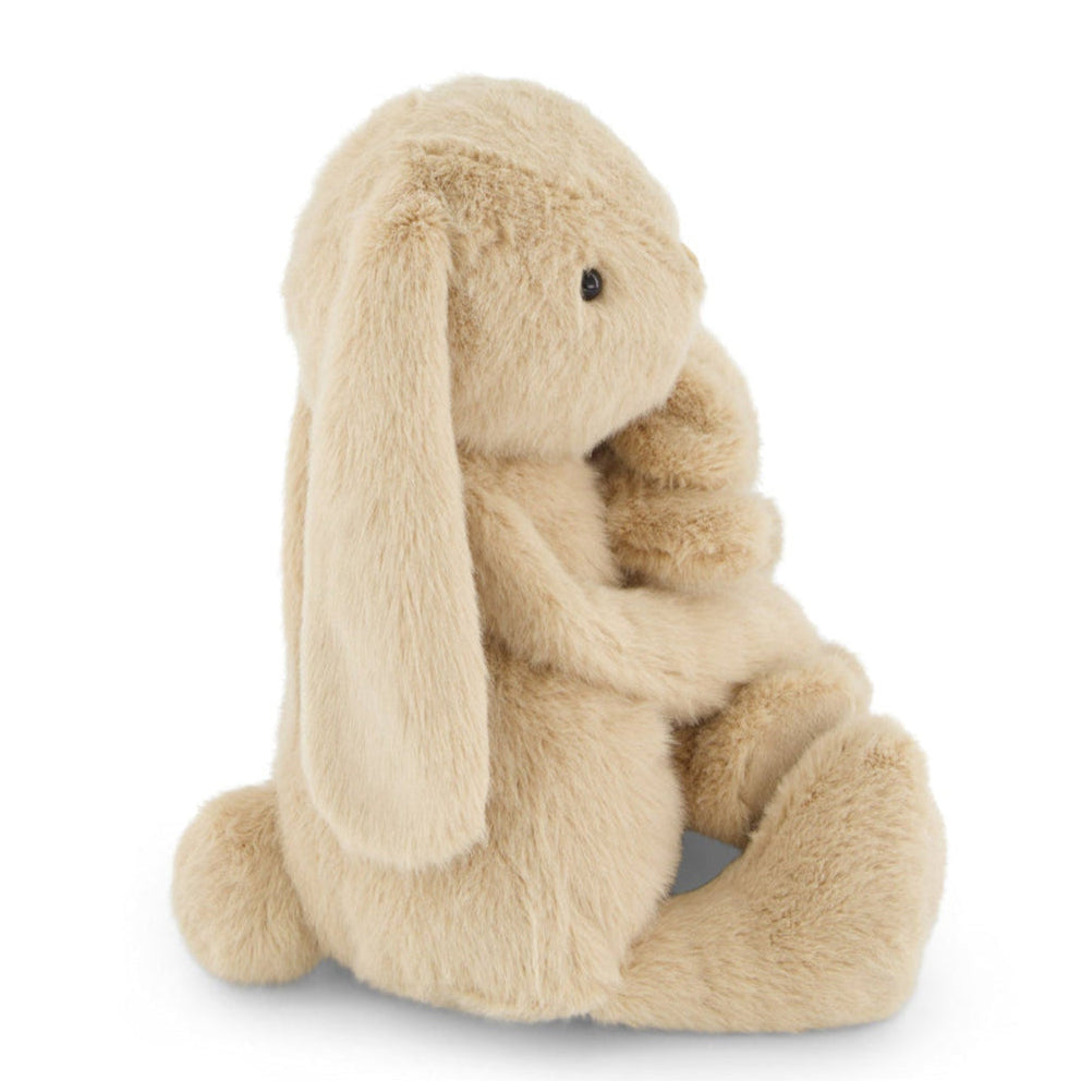 Side view of a plush, tan bunny rabbit toy sitting.