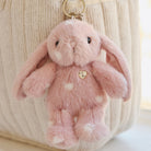 Pink plush bunny keychain with white dots and a heart-shaped button.