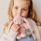 Girl holding pink plush bunny.
