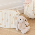 Close-up of a beige quilted bag with a teddy bear pattern, featuring a plush bunny keychain attached.