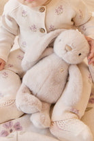 Infant in floral knitwear holding a plush bunny.