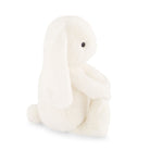 Side view of a fluffy white bunny plush toy sitting upright.