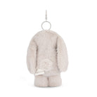 Back of a furry, beige rabbit keychain with a silver clip and a white label.