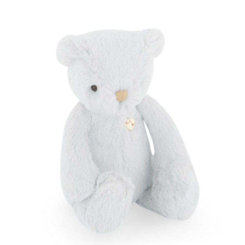 Light blue plush teddy bear with heart-shaped button.