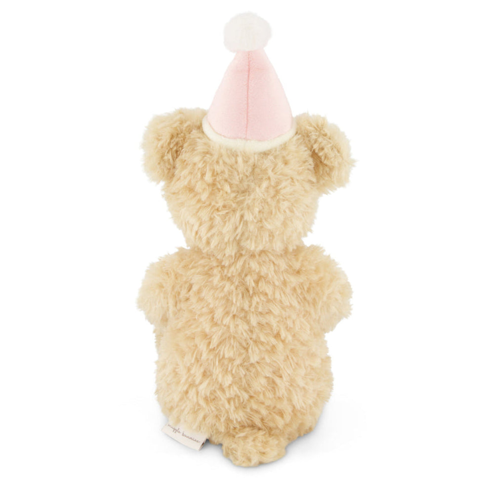 Back view of a beige teddy bear wearing a pink party hat.