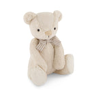 Cream-colored plush teddy bear with striped bow tie, sitting.