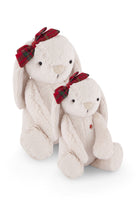 Two fluffy white bunny plush toys, one taller behind the other, both with red and green plaid bows on their heads.