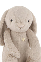 Stuffed bunny toy, beige plush fabric, heart-shaped button.