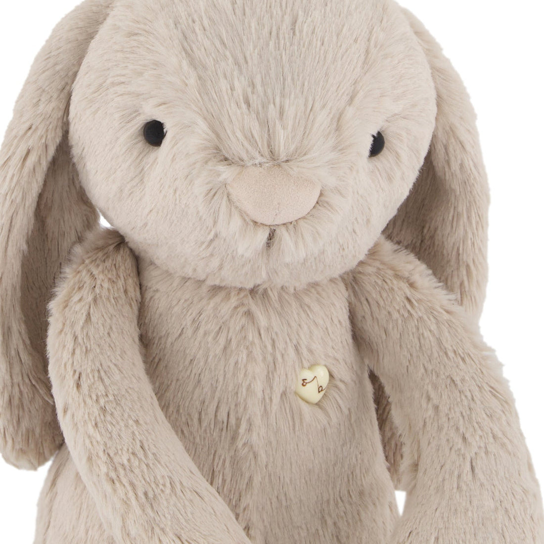 Stuffed bunny toy, beige plush fabric, heart-shaped button.