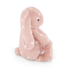 Pink plush bunny toy with white hearts, sitting.