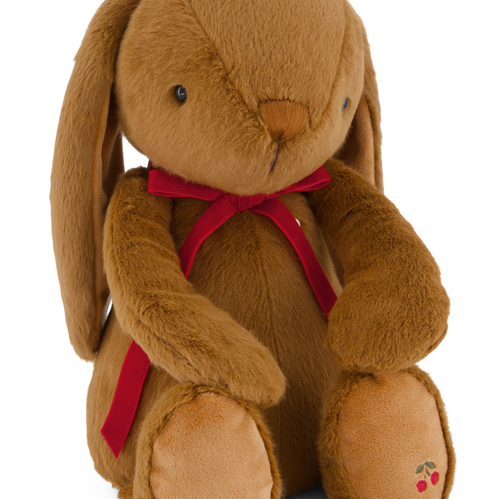 Brown plush bunny with a red bow tie on a white background