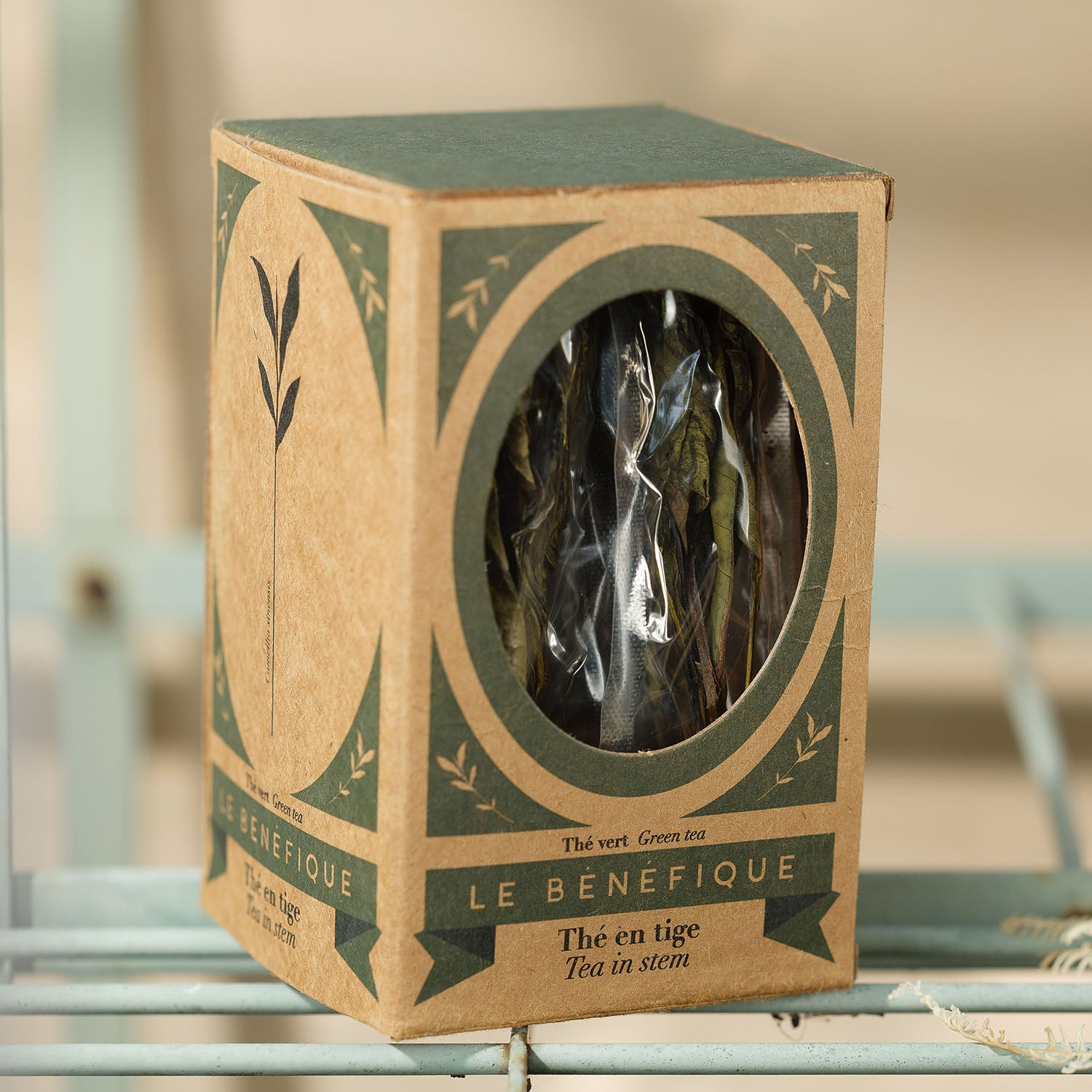 A box of "Le Benefique" green tea with a round cutout showing the tea inside.