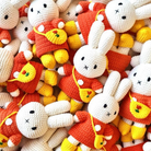 Pile of crochet bunny dolls wearing orange dresses with yellow shoes and small purses.