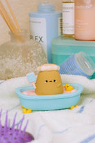 Clay figure in a blue bathtub, spa scene, towel background.