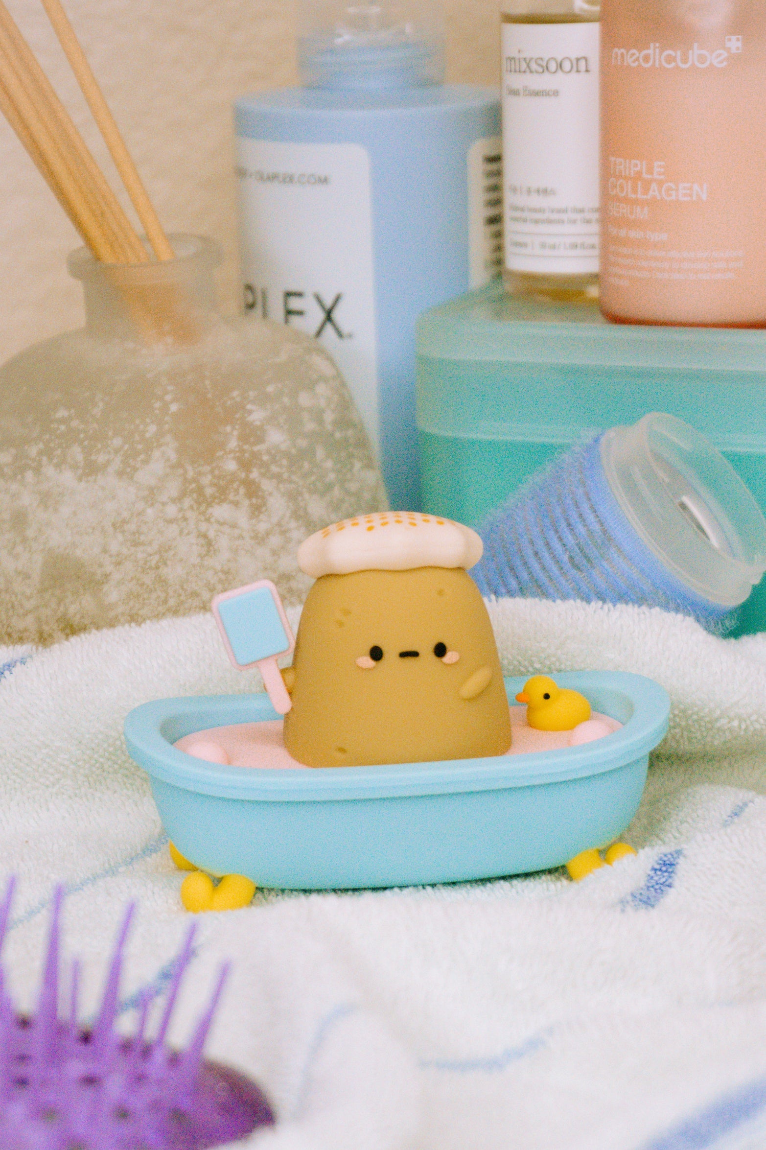Clay figure in a blue bathtub, spa scene, towel background.