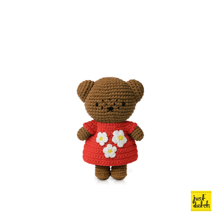 Crocheted brown bear wearing a red dress with white flowers.