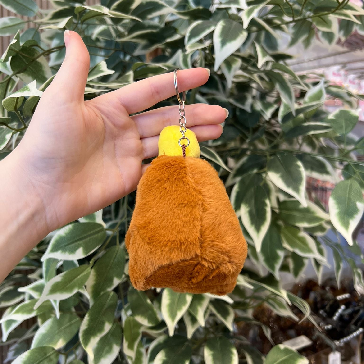 Hand holding a brown and yellow fur keychain.