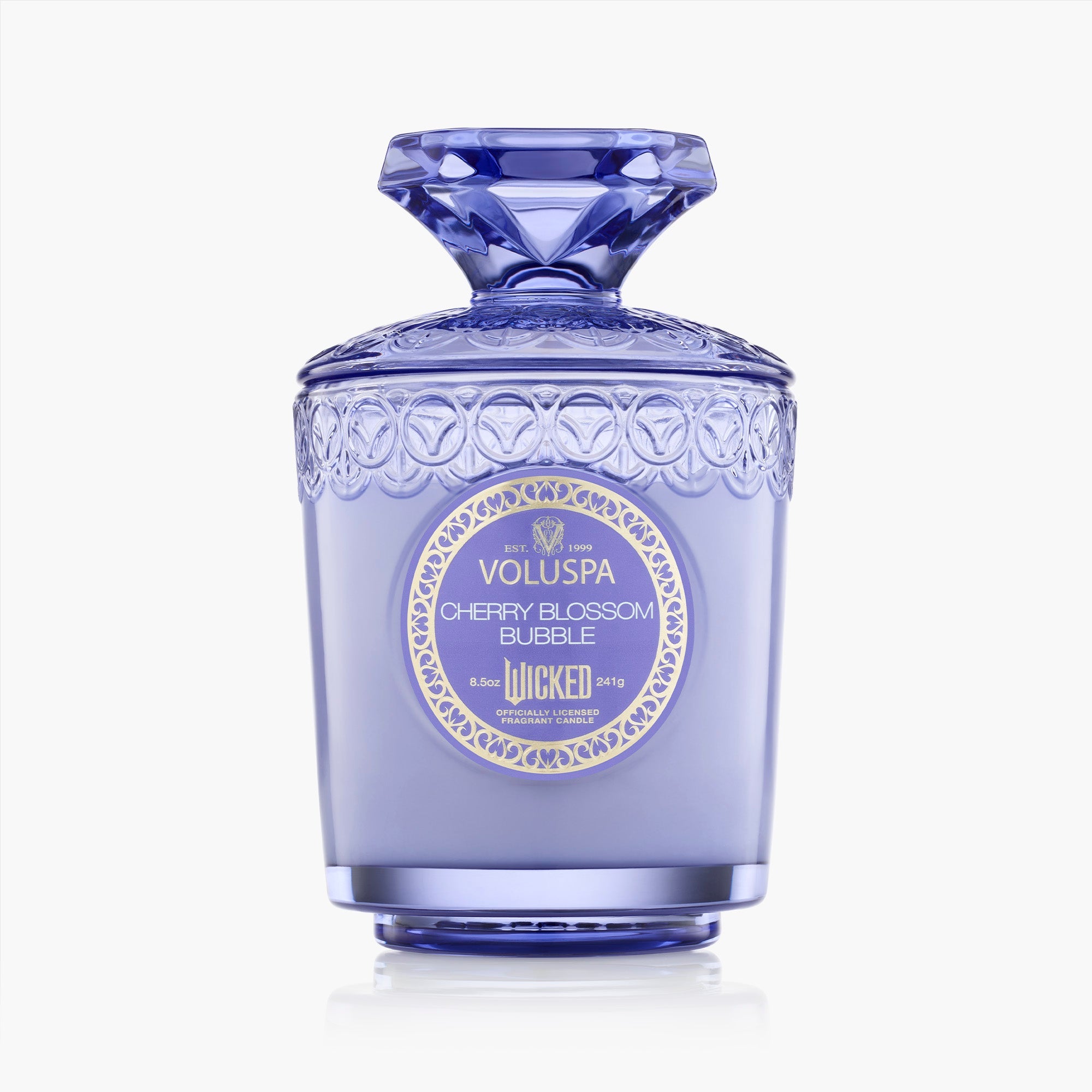 Decorative purple candle with intricate design and Voluspa branding on a white background