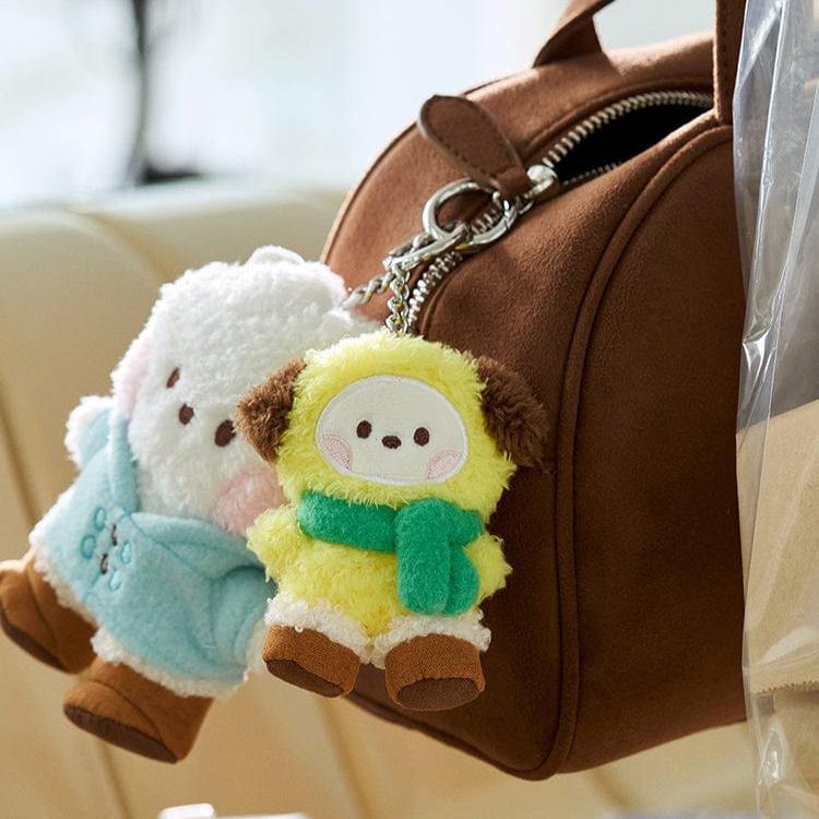 Two plush keychains hanging from a brown handbag.