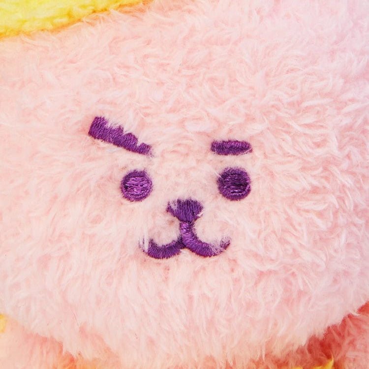 Close-up of a pink plush toy with embroidered purple facial features.