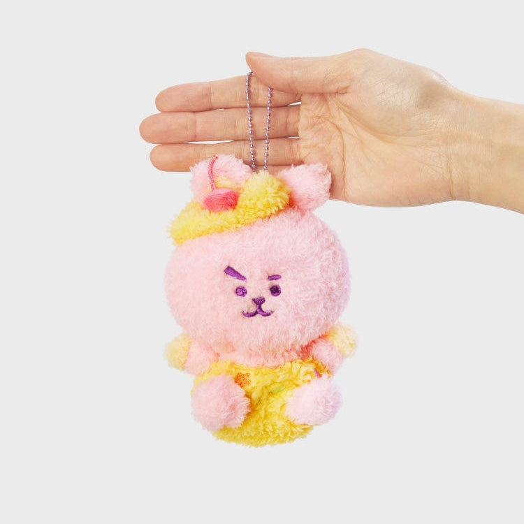 A hand holding a pink and yellow plush keychain.