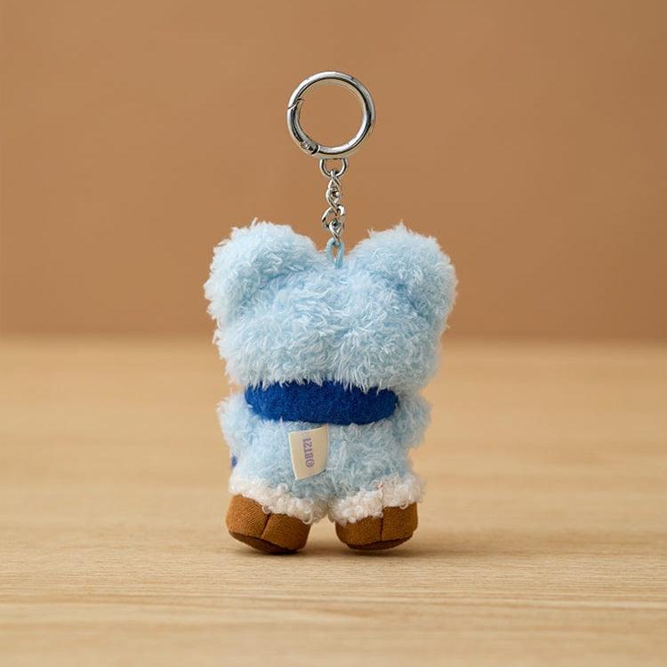 Back view of a blue teddy bear keychain with a blue scarf and brown feet.